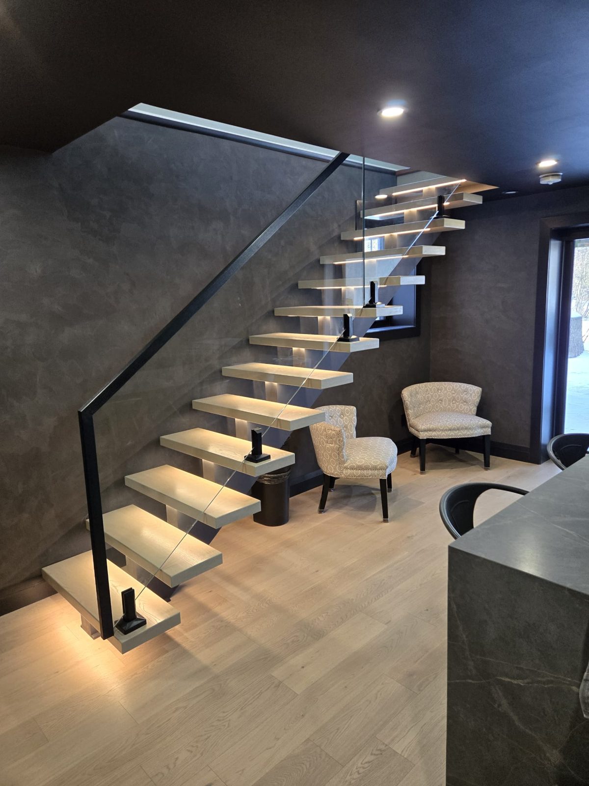 Floating stair with lit treads and a matching handrail, wired by HausPower