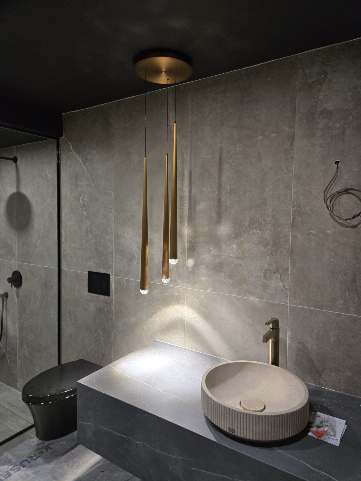Powder room with brass pendant lights over a stone vanity, by HausPower